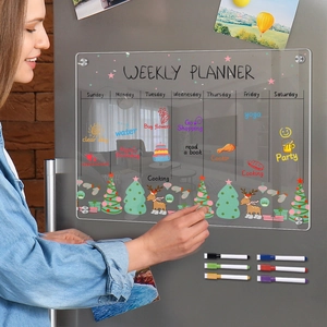 Close-up of a woman writing on a magnetic acrylic weekly planner on a refrigerator