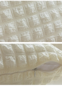 Detail of white quilted puff fabric texture and hidden zipper on sofa cushion cover