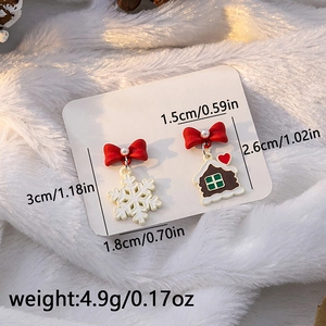 Macro detail of asymmetric Christmas earrings with snowflake and gingerbread house design