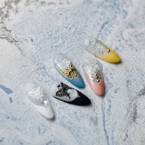 Detailed view of 5D nail art tips featuring gold butterfly reliefs and 3D floral accents