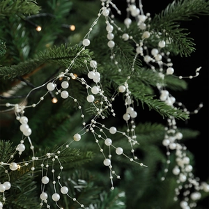 White pearl bead garland garland draped on a Christmas tree branch with warm festive lights