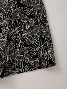 Close-up of white leaf embroidery details on premium black fabric skirt shorts