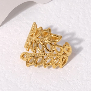 Detailed view of the hollow gold leaf adjustable ring on a white textured surface