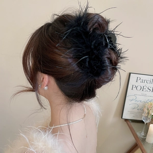 Elegant black feather hair claw clip on model's hairstyle with soft lighting background