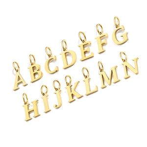Flat lay of 14 gold metal alphabet charms A to N with glossy finish and round jump rings