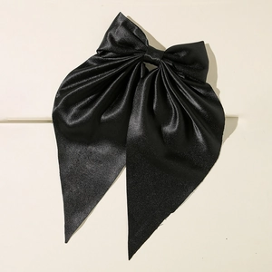 Elegant oversized black satin bow hair clip with a luxurious silky texture on a white surface