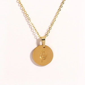 Detailed close-up of a gold oval titanium necklace pendant with floral rose engraving