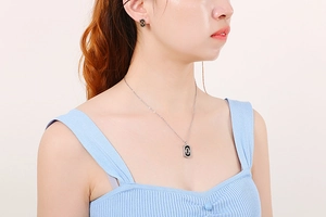 Close-up of model wearing silver paperclip chain necklace and black inlay earring set