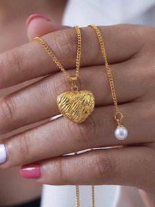 Vue macro d'un collier pendentif cœur tressé doré avec une petite perle blanche