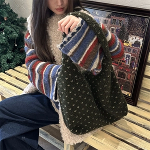 Sac fourre-tout vert en polaire à motifs de cœurs blancs porté dans un décor d'hiver