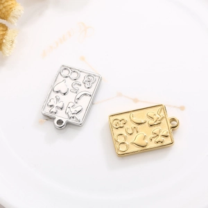Detail of silver and gold stainless steel charms with heart and clover patterns