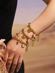 Detailed view of layered gold bracelets with zircon charms and textured floral ring