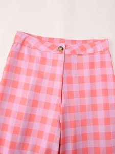 Detail of pink and orange plaid trousers featuring waist button and zipper fly design
