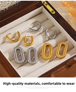 Macro detail of 18K gold and silver geometric oval hoop earrings with spiral textures