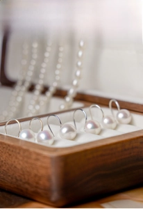 Detailed view of 8-9mm white freshwater pearl earrings with s925 silver hooks on velvet