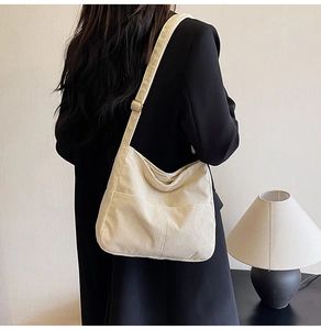 Model wearing a beige corduroy hobo bag with large exterior pockets on a shoulder