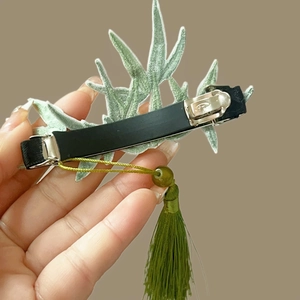 Detailed back view of green bamboo leaf hair clip with metal spring and tassel