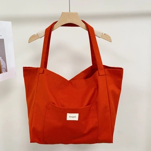 Close-up of orange canvas tote bag showing the front pocket and white Bonogeed brand tag