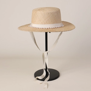 Detailed texture of boater hat with pearl trim and long white ribbon ties