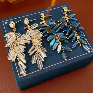 Close-up of dangling rhinestone earrings in clear and deep blue on a blue gift box