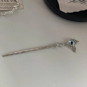 Close-up of surreal silver eyeball hair stick with liquid metal fringe and hammered texture