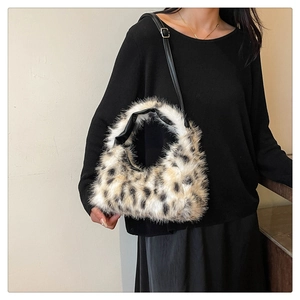 Detail of plush leopard print handbag with black leather strap on a model