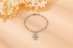 Detailed close-up of a silver stainless steel Hamsa Hand bracelet with a Figaro chain