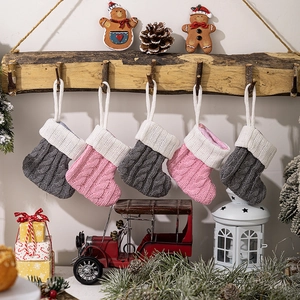 Detailed close-up of five knitted Christmas stockings in pink and grey hanging on hooks