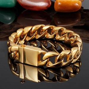 Detail shot of a thick gold Cuban link bracelet on a sleek black reflective base