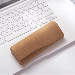 Detailed view of brown nubuck sunglasses case placed on a modern laptop keyboard