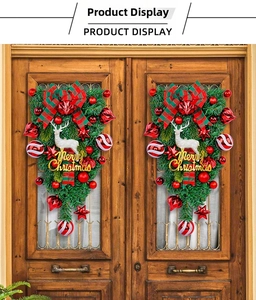 Christmas teardrop wreath with reindeer, red baubles, and plaid bow on dark wooden doors
