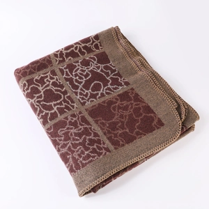 Détail d'un châle en tricot vintage montrant le motif floral bordeaux et les bords cousus