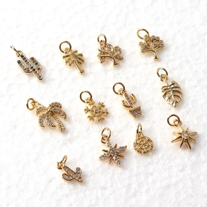 Detailed view of gold-plated charms including cactus, palm tree, and star with crystals