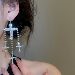 Detail of silver cross tassel earrings with sparkling rhinestones worn by a female model