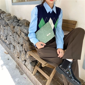 Close-up of a green corduroy makeup bag held by a model in a retro style outdoor scene