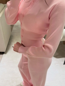Detailed knit texture of pink long sleeve button-up cardigan and matching trousers set