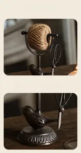 Close-up of vintage cast iron bird twine holder with antique scissors on wooden desk