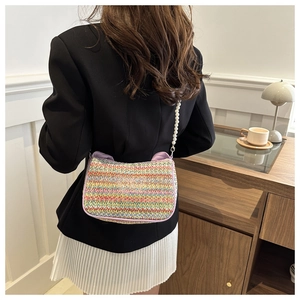 Détail d'un sac bandoulière en paille arc-en-ciel avec anse en perles sur un mannequin