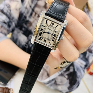 Close-up of rectangular silver watch with roman numerals on black leather strap