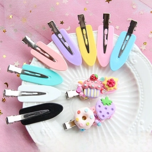 Detail of colorful DIY duckbill hair clips with cream glue charms on white porcelain plate