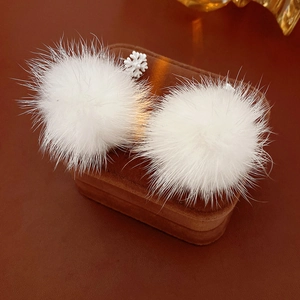 Macro view of white snowflake charm and fluffy fur ball on a velvet jewelry box