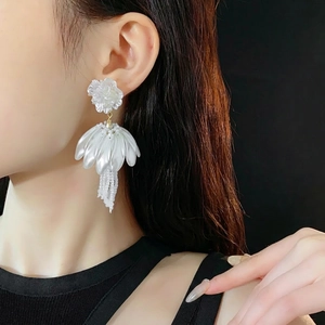 Elegant white floral petal earrings with beaded tassels on model with black background