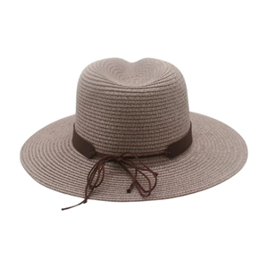 Détail d'un chapeau de paille avec texture tissée fine et ruban décoratif marron foncé