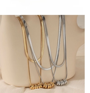 Detail of gold and silver double-layered snake chain necklaces with circular pendants