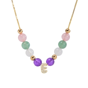 Détail d'un collier en perles multicolores avec un pendentif lettre E serti de zircons