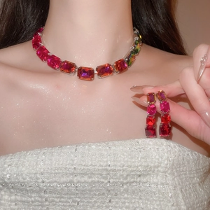 Close-up of vibrant square-cut gemstone necklace and earrings on model wearing white tweed