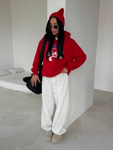 Dettaglio della felpa rossa oversize con stampa e pantaloni della tuta grigi larghi