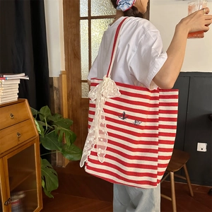 Detail of red striped canvas tote with white lace bow and elegant embroidery