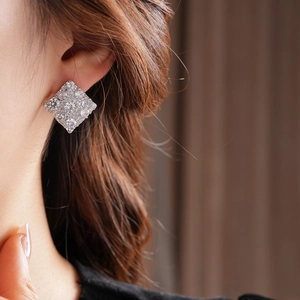 Gros plan d'une boucle d'oreille carrée en zircon sur l'oreille avec finition argent