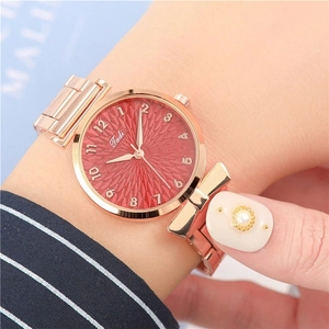 Close-up of rose gold watch with red radial dial and bow-shaped case connector detail